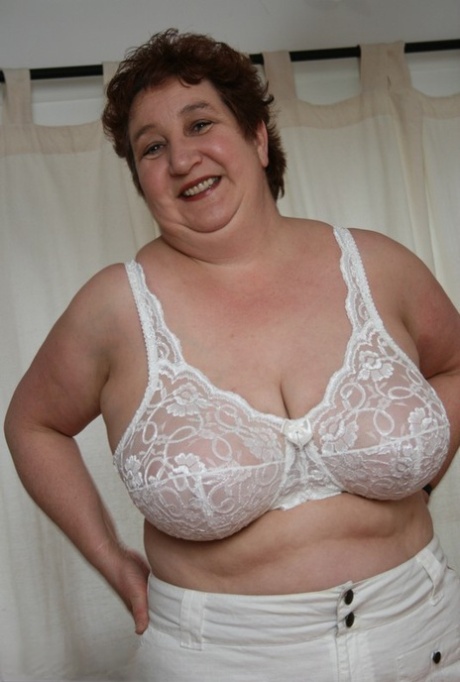 Standing on a dining table next to her adult body, BBW Kinky Carol lets out her massive breasts.