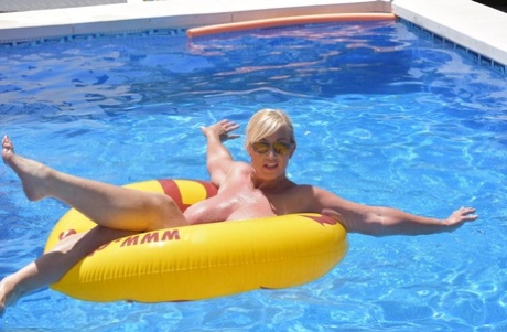 In a swimming pool, Melody, a blonde amateur, displays her plump figure.