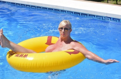 Melody, a blonde amateur, displays her plump physique while swimming in a pool.