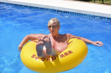 Melody, a blonde amateur athlete, displays her plump physique while swimming in a pool.