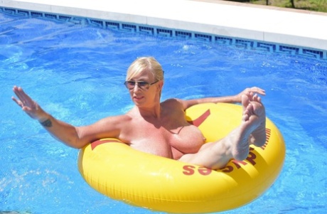 Melody, who is a blonde amateur athlete, displays her plump figure while swimming in a pool.