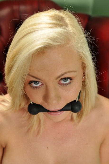 A topless blonde named Sarah Jane is confined in the gag position with her wrist and ankle exposed.