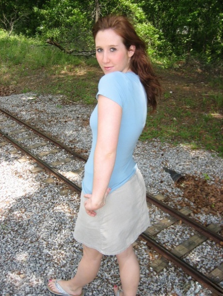 Nail up: Pale redhead exposes her tiny boobs close to model railroad tracks.