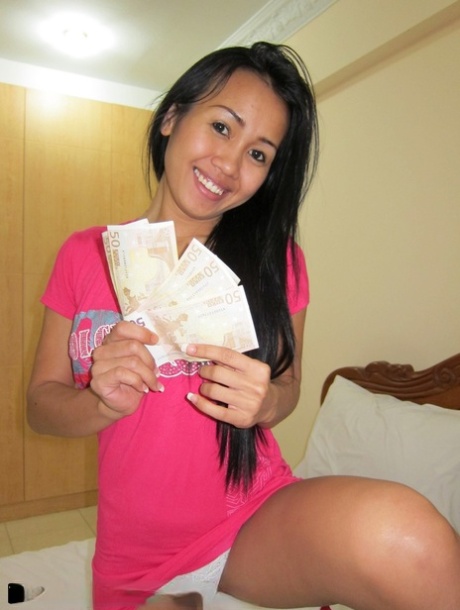 A Thai woman wearing clothes exchanges her pink dress for a fistful of money.