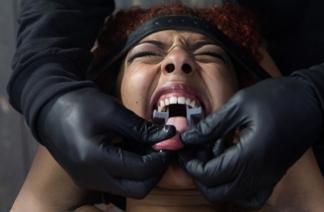 The restrained black girl shouts in pain as she is tortured by a sadist.