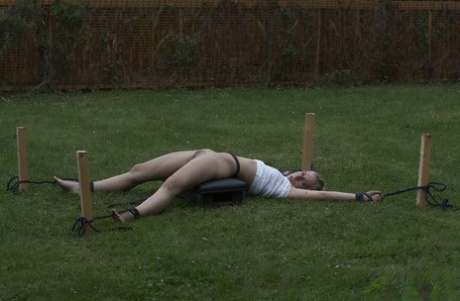A young blonde girl is tortured by her captor in the backyard.