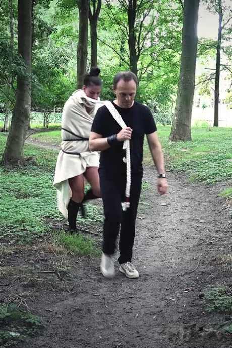 A young brunette slave is supervised by her Master and subjected to discipline in the woods.