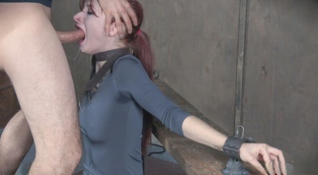 Violet Monroe, a redhead sex slave, is made to perform a deep-throated sexual act.