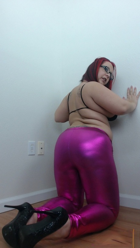 The solo girl, Georgia Peach, displays her large tits and belly bump while wearing purple pants.