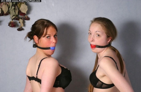 Girls wearing black bras and thong outfit are tied up after being ballgagged by another woman.