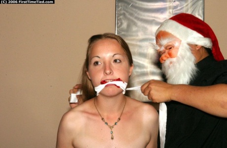 An ordinary girl is subjected to handcuffing and gauring by a man wearing a Santa mask.