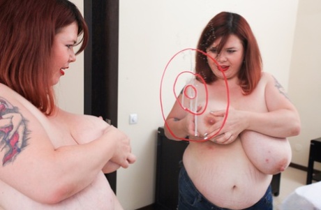 Roxanne Miller, an overweight redhead, expels milk from her massive breasts.