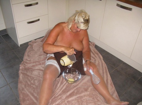 Chrissy Uk, a middle aged woman with blonde hair and plumage, covers her mostly unclothed body in battered corpses.
