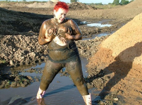 The overweight body of Valgasmic Exposed, a young redhead, is covered in thick mud.