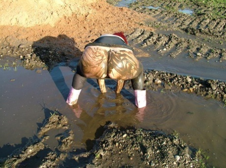 The exposed young reddest body of Valgasmic Exposed is covered in mud at her waist.