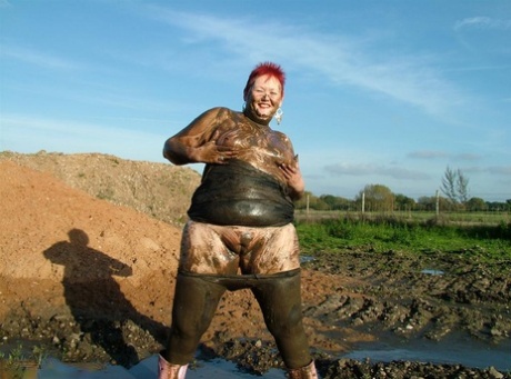 Fat woman with adult red hair, named Valgasmic Exposed, dips into the mud to hide her excess weight.