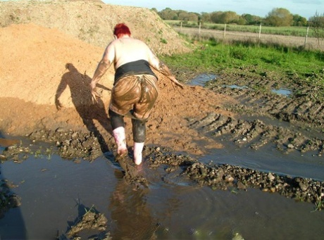 A matured redhead named Valgasmic Exposed is covered in mud to hide her excess body fat.