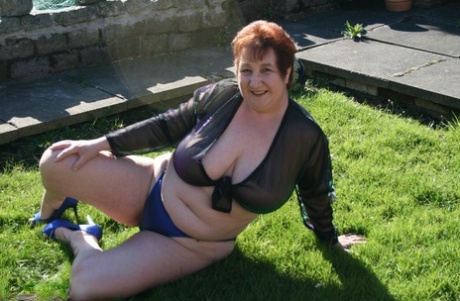 BBW Kinky Carol, who is now an adult redhead, releases her large breasts in the yard.