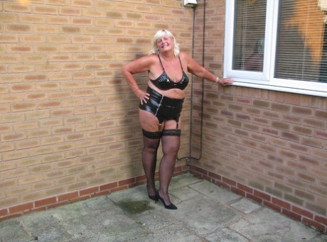 Aged 40-year-old blonde Chrissy Uk wears a topless outfit while washing her windows outside.