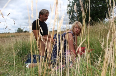 Older British males are hit on the doggystyle by a blanket in front of an open hay field.