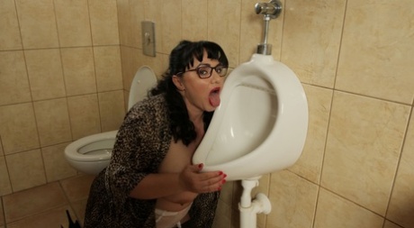 Big Titted Brunette Mistress Sarah Licks A Men's Urinal While Wearing Glasses