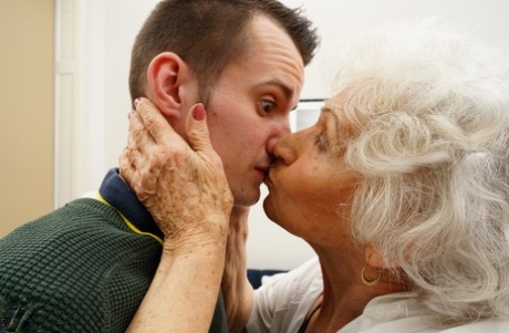 The older female partner kisses a young man while seducing him for an essential sexual encounter.