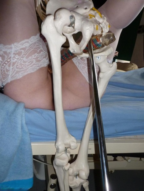 An older redhead nurse named Valgasmic Exposed is whipped by a dildo with a skeleton attached to her body.