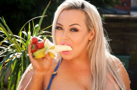 BBW Jem Stone, with his big blonde heels in mismatched colors, enjoys a banana on the patio.