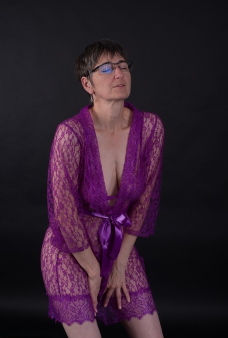 Modeling in purple lingerie, the elderly individual sports short hair and does not wear makeup.