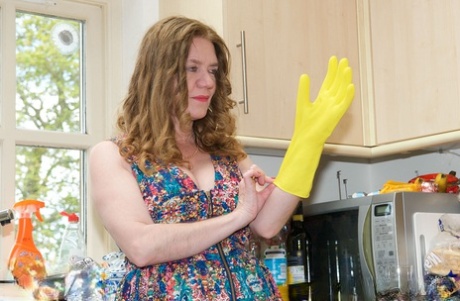 With rubber gloves on her back, Lily May uncovers the size of her large tits while working as an adult housewife.