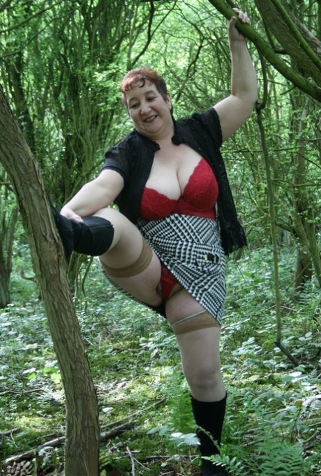 Mature lady Kinky Carol shows her huge tits and butt amid undergrowth