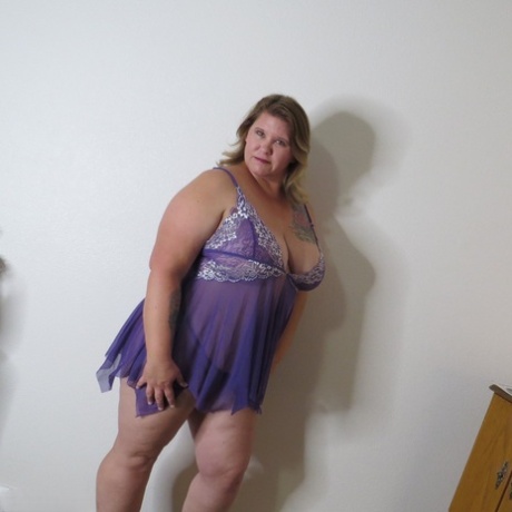 While doffing lingerie, Busty Krisann, an overweight lad, stands naked against a wall.