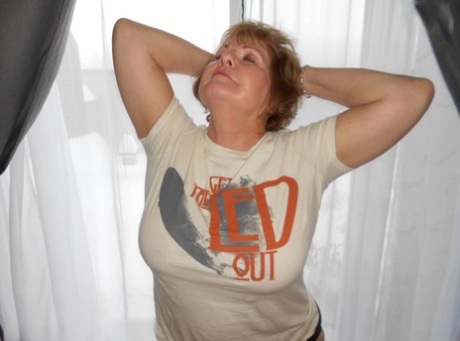 Busty Bliss, an older and chubby woman, loses her sizable breasts from a T-shirt.