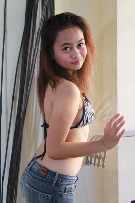 A young Asian girl named Rochelle exhibits her balding pussy after stripteasing.