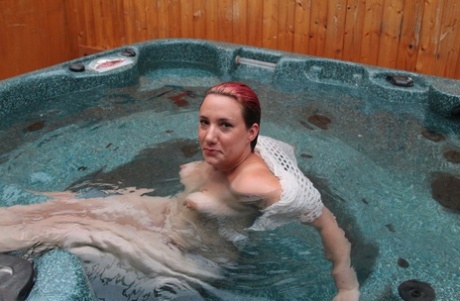 Sara Banks, a young and well-built woman, goes for a complete nude swim in an outdoor hot tub.