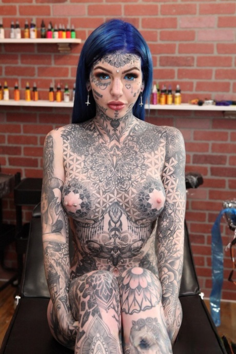 Heavily tattooed girl Amber Luke poses naked in a tattoo shop.