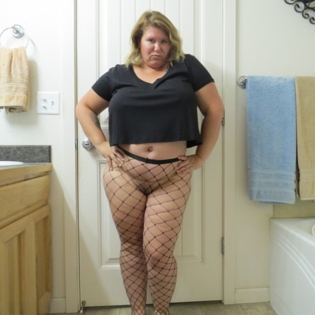 Overweight amateur Busty Krisann models herself with fishnet pantyhose and displays her oversized breasts.