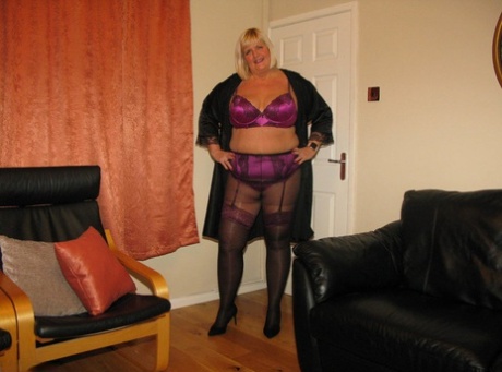 Older blonde BBW Chrissy Uk models lingerie & pantyhose on a leather loveseat