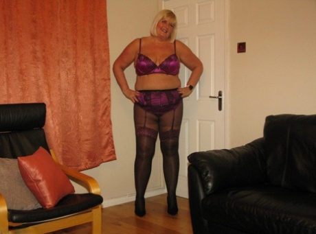 BBW Chrissy Uk, who is blonde and has blonde hair, models a leather loveseat covered in lingerie with pantyhose.