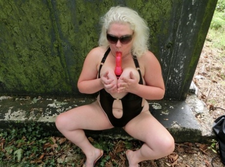 By using a vibrator in her mouth while in nature, Barby, a mature platinum blonde, engages in self-pleasure.