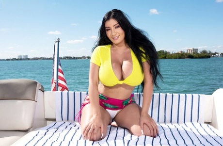 During a boat ride, Selena Adams, a Latina woman with dark hair, displays her prominent breasts.