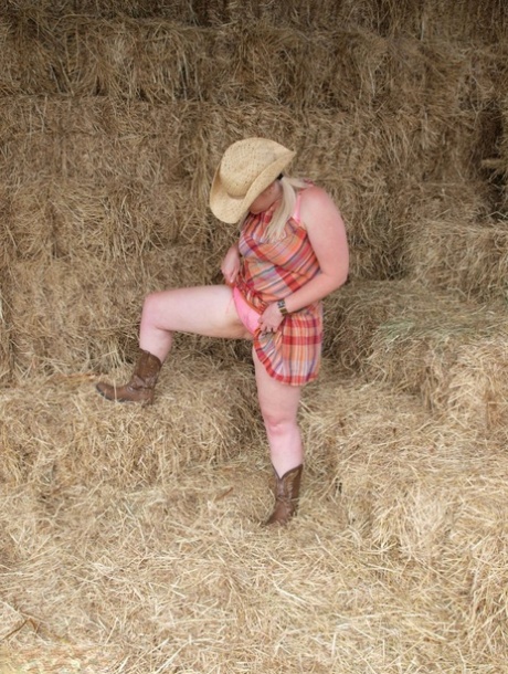 Samantha, an amateur BBW on the side of a haymow, exposes herself in cowgirl boots and a hat.