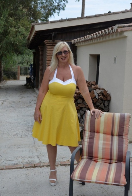 Melody, a thick, adult blonde, looses her big tits and buttocks while wearing a yellow dress.