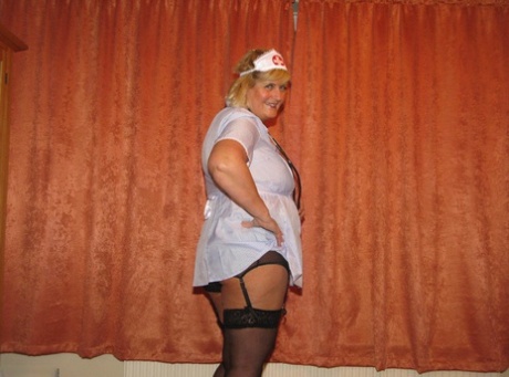 Drunken nurse Chrissy Uk removes her surgical mask and uniform to showcase lingerie for the camera.