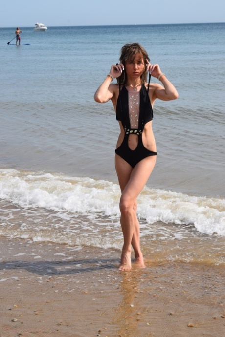 Slender females pose for a picture in a bathing suit at a deserted beach.