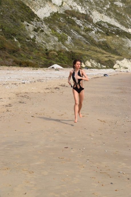 Thin women showcase a bathing suit while enjoying the view at an empty beach.