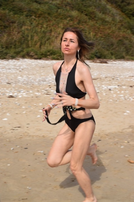 A beach is deserted, and slender women pose in a bathing suit.