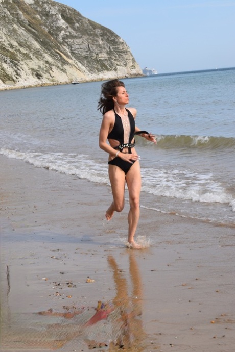 At a deserted beach, petite women showcase a swimsuit while enjoying the scenery.