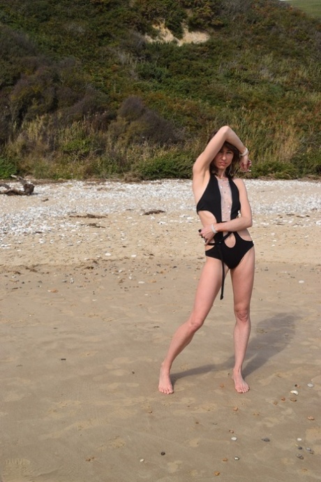 The sight of a deserted beach is captured on camera as slim females pose in a bathing suit.