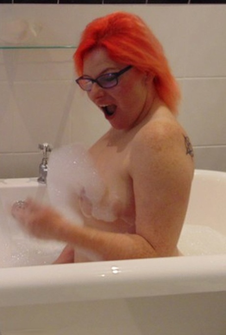 With her glasses on, Mollie Foxxx, an amateur with a tattoo, takes a bubble bath while being bathed.